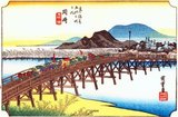 Okazaki: A daimyo's cortège crossing the bridge over the Yahagi River towards the village and castle on the further bank; in the background a blue hill, printed from colour blocks only.<br/><br/>

Tokugawa Ieyasu, the founder of the Tokugawa Shogunate, was born in the castle shown in the prints. The bridge over the Yahagi River, flowing west of the castle, was the largest on the entire highway.<br/><br/>

Utagawa Hiroshige (歌川 広重, 1797 – October 12, 1858) was a Japanese ukiyo-e artist, and one of the last great artists in that tradition. He was also referred to as Andō Hiroshige (安藤 広重) (an irregular combination of family name and art name) and by the art name of Ichiyūsai Hiroshige (一幽斎廣重).<br/><br/>

The Tōkaidō (東海道 East Sea Road) was the most important of the Five Routes of the Edo period, connecting Edo (modern-day Tokyo) to Kyoto in Japan. Unlike the inland and less heavily travelled Nakasendō, the Tōkaidō travelled along the sea coast of eastern Honshū, hence the route's name.